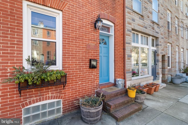 view of exterior entry featuring brick siding and visible vents