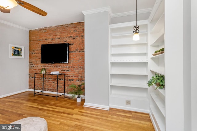 living room with baseboards, built in features, ceiling fan, wood finished floors, and crown molding