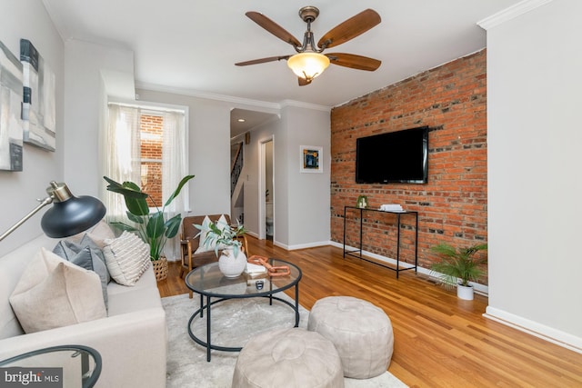 living room with ornamental molding, ceiling fan, baseboards, and wood finished floors