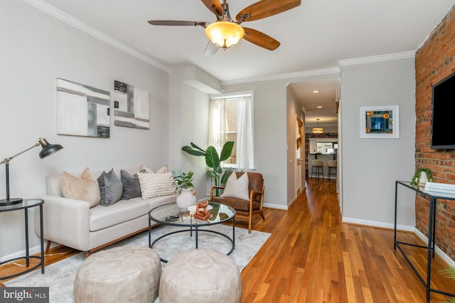 living area featuring crown molding, baseboards, ceiling fan, and wood finished floors