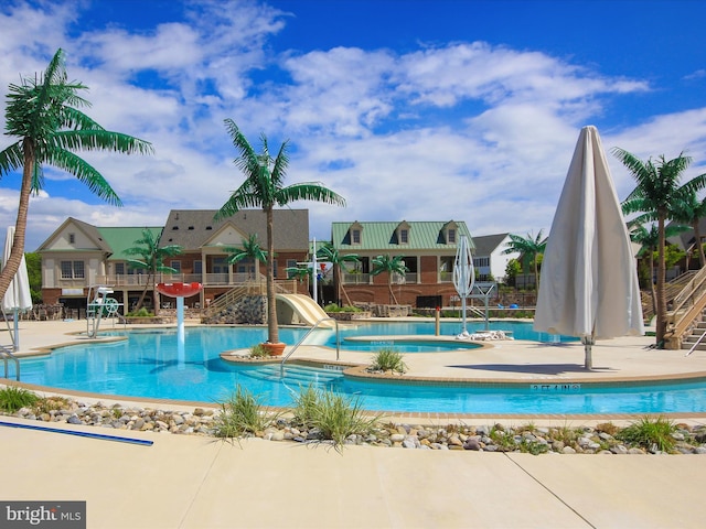 view of swimming pool featuring a hot tub, a patio area, and a water slide