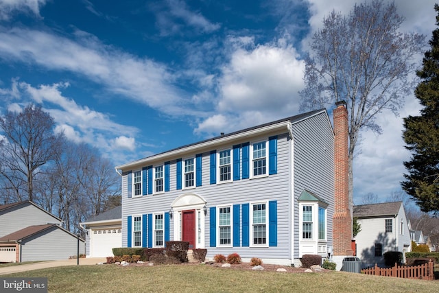 colonial house with cooling unit, a front yard, driveway, and a chimney