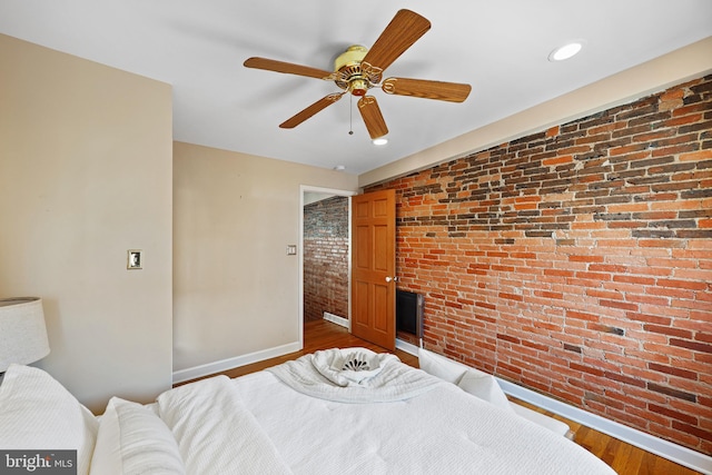 bedroom featuring recessed lighting, ceiling fan, brick wall, wood finished floors, and baseboards