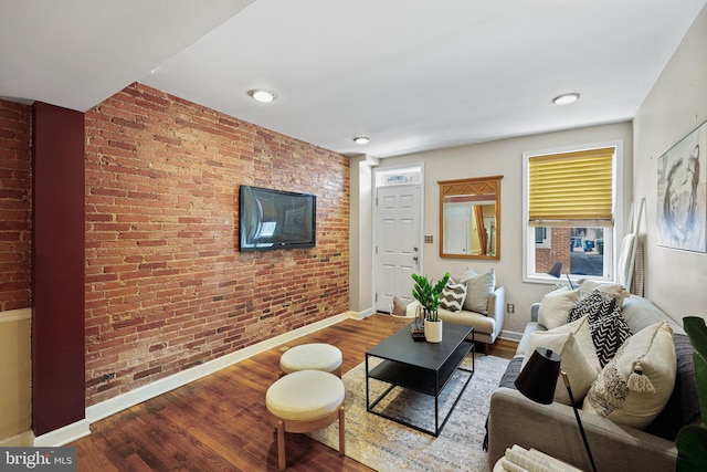 living room featuring brick wall, baseboards, and wood finished floors