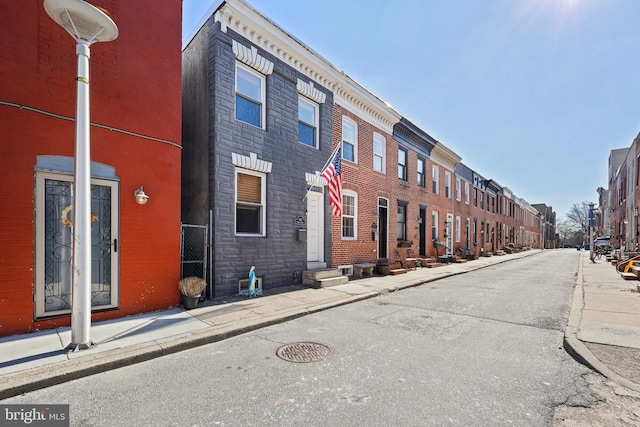 view of street with sidewalks, entry steps, and curbs