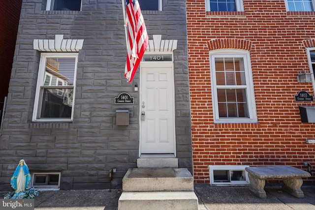 entrance to property featuring stone siding and brick siding