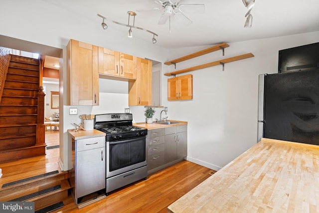 kitchen featuring light wood-style flooring, gray cabinets, stainless steel appliances, light brown cabinetry, and a sink