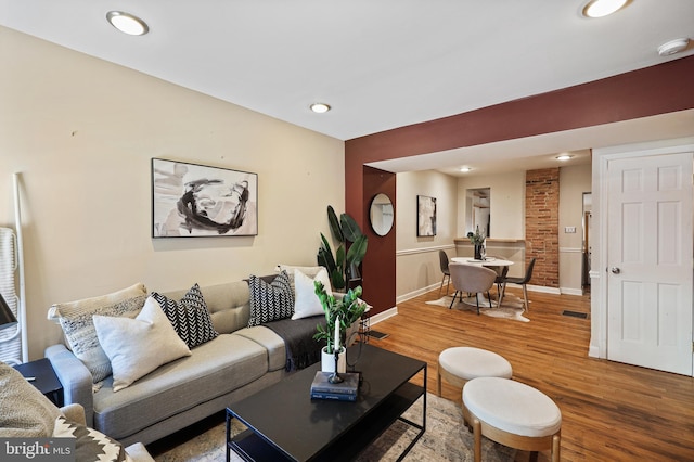 living room with recessed lighting, visible vents, baseboards, and wood finished floors