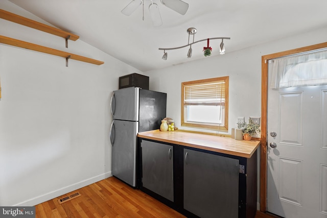 kitchen with freestanding refrigerator, visible vents, wooden counters, and light wood-style flooring