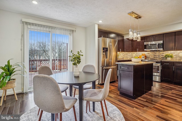 dining area with dark wood-type flooring, recessed lighting, a textured ceiling, and an inviting chandelier