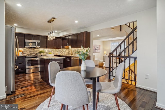 dining area with dark wood-style flooring, a textured ceiling, baseboards, and stairs