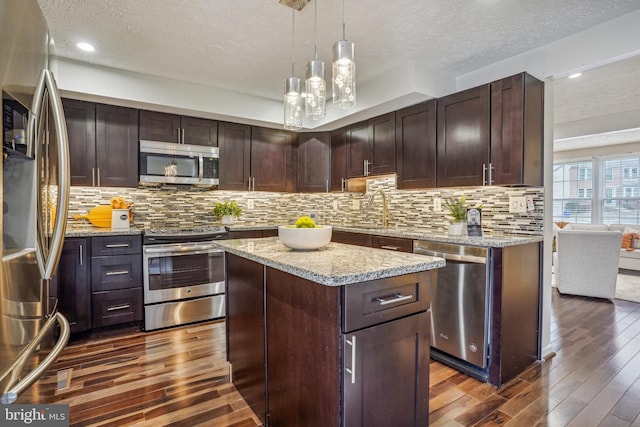 kitchen with dark wood finished floors, tasteful backsplash, appliances with stainless steel finishes, dark brown cabinetry, and a sink