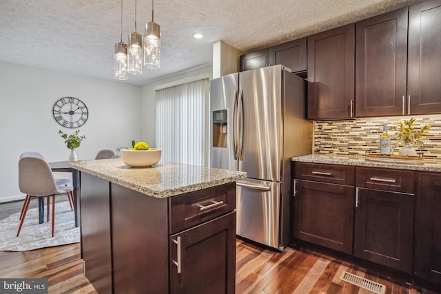 kitchen with tasteful backsplash, stainless steel fridge, visible vents, and dark wood finished floors