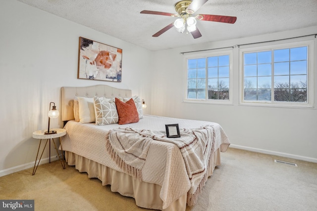 bedroom featuring light carpet, baseboards, visible vents, and a textured ceiling