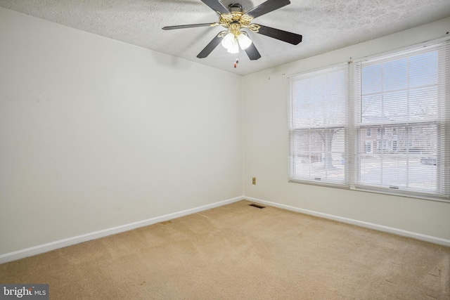 empty room featuring light colored carpet, a textured ceiling, and baseboards