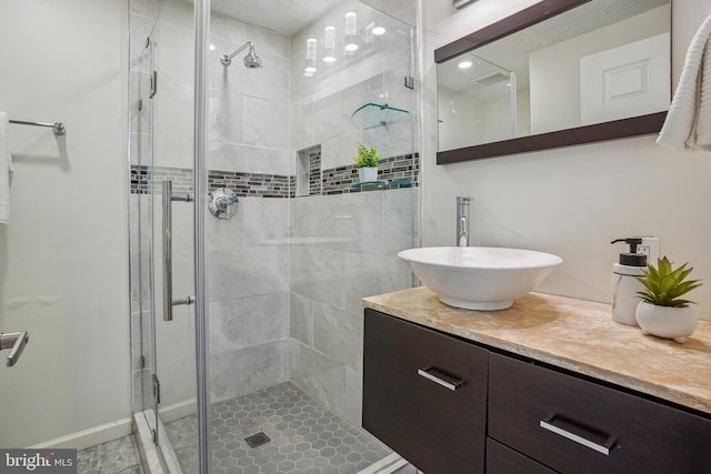 bathroom featuring a stall shower, vanity, and baseboards