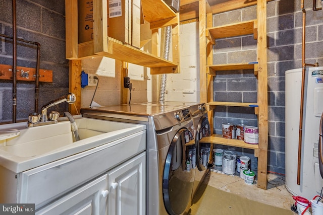 clothes washing area with concrete block wall, laundry area, washer and clothes dryer, electric water heater, and a sink