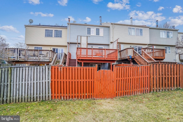 rear view of property featuring a fenced backyard, stairway, and a deck