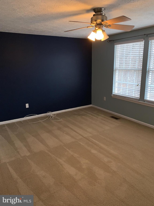 unfurnished room with a textured ceiling, baseboards, visible vents, and light colored carpet