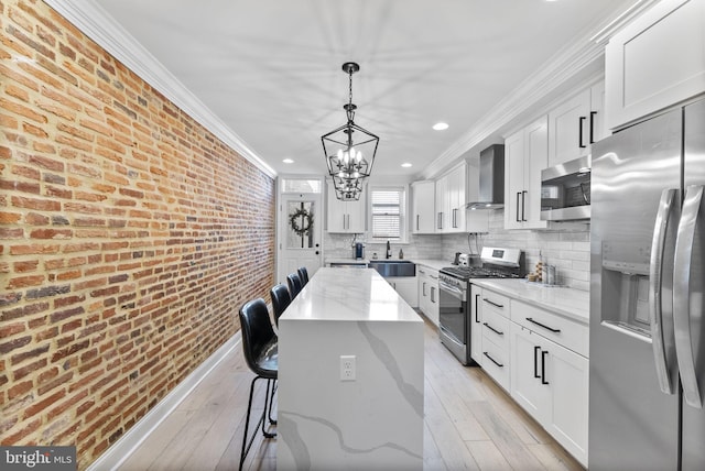 kitchen featuring stainless steel appliances, brick wall, light wood-style floors, wall chimney exhaust hood, and crown molding