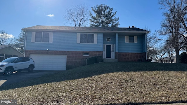 bi-level home with driveway, brick siding, and an attached garage