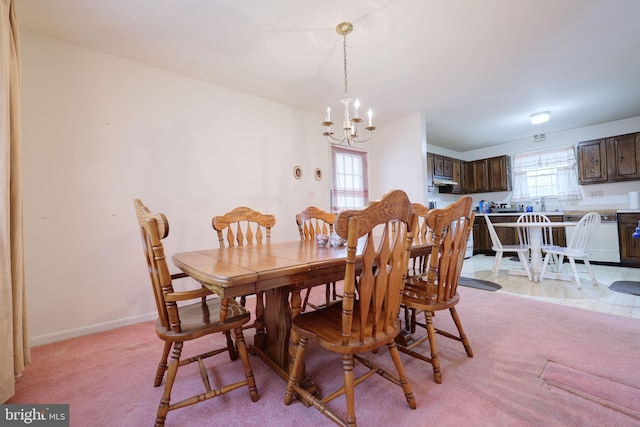 dining space featuring a chandelier, light colored carpet, plenty of natural light, and baseboards