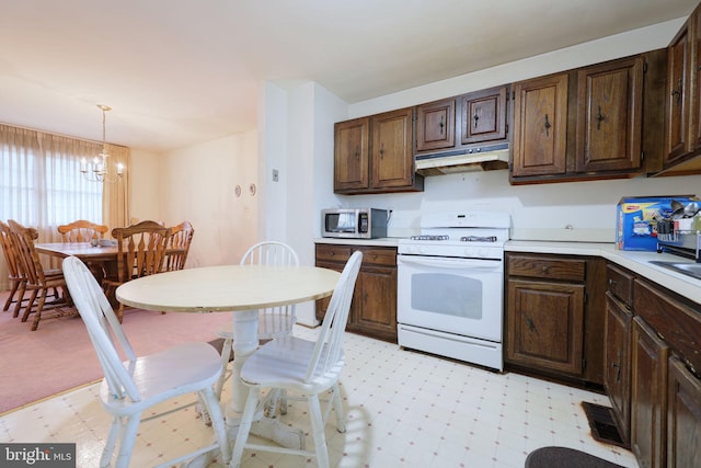 kitchen featuring under cabinet range hood, pendant lighting, light countertops, and white gas stove