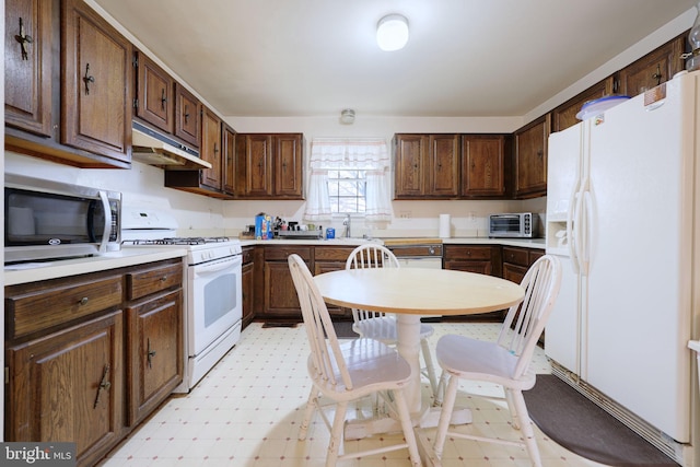 kitchen featuring a toaster, light floors, light countertops, white appliances, and under cabinet range hood