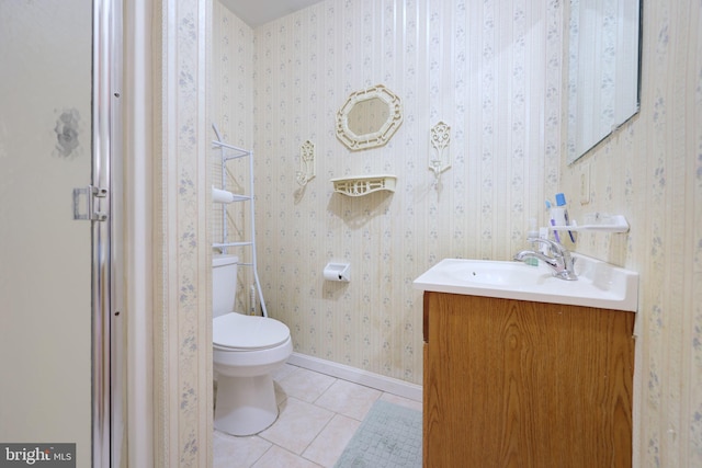 bathroom featuring tile patterned flooring, toilet, vanity, baseboards, and wallpapered walls