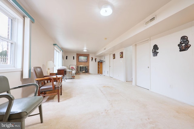 sitting room with light carpet, a wealth of natural light, a fireplace, and visible vents