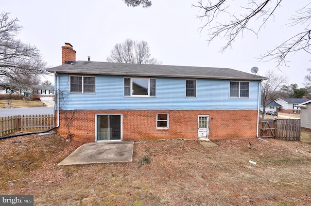 back of house with a patio area, fence, a chimney, and brick siding