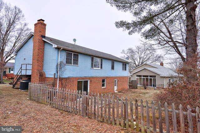 rear view of house with fence private yard, stairs, and a chimney