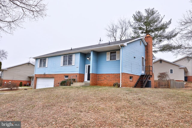 split foyer home with an attached garage, a chimney, and brick siding