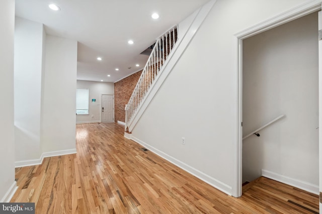 interior space featuring baseboards, brick wall, stairway, light wood-style floors, and recessed lighting