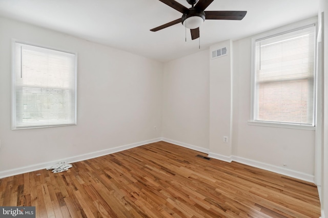 spare room featuring visible vents, ceiling fan, baseboards, and wood finished floors