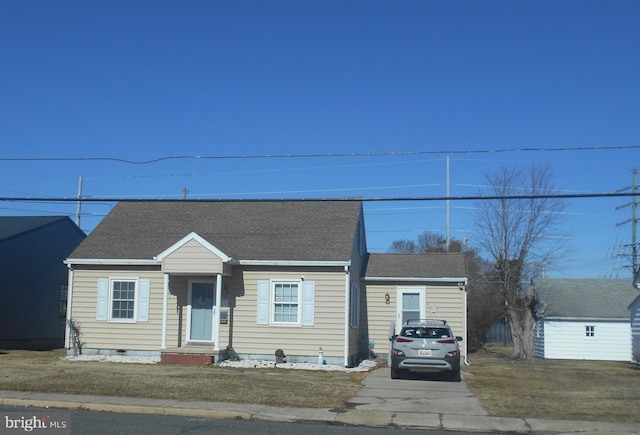 bungalow-style home with a front yard and a storage shed