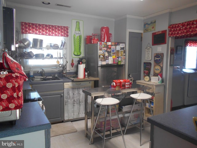 kitchen with gray cabinetry, dishwashing machine, stainless steel refrigerator, sink, and ornamental molding