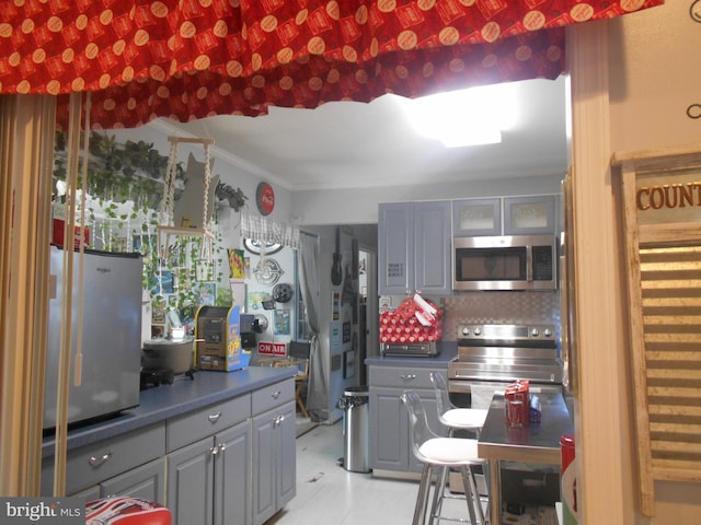 kitchen featuring crown molding, tasteful backsplash, gray cabinetry, and stainless steel appliances