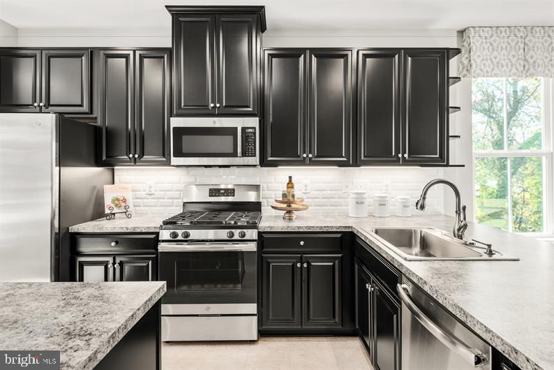 kitchen with appliances with stainless steel finishes, sink, tasteful backsplash, and a wealth of natural light