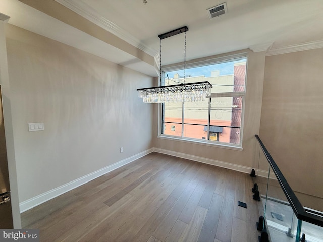 unfurnished dining area with ornamental molding, wood finished floors, visible vents, and baseboards