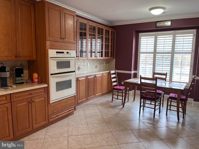 kitchen with brown cabinetry, double oven, glass insert cabinets, and light countertops