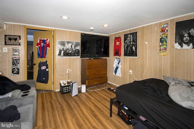 bedroom featuring wood walls, wood finished floors, and recessed lighting