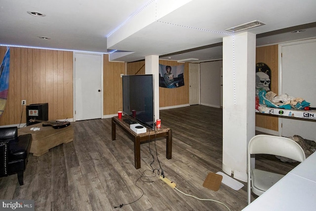 living room with wood walls, visible vents, and wood finished floors