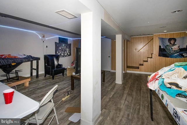 interior space featuring dark wood-style floors, visible vents, stairway, and wooden walls