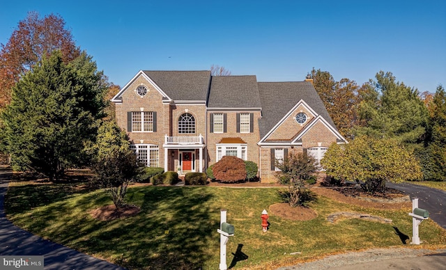 georgian-style home featuring a front lawn and brick siding