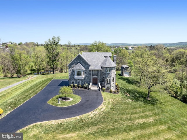 view of front of home with a chimney, a front lawn, aphalt driveway, and stone siding