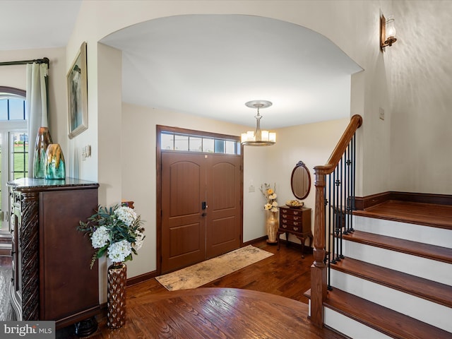 entrance foyer with baseboards, stairs, wood finished floors, and a chandelier