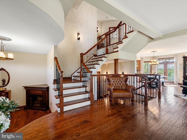 stairs featuring wood-type flooring, baseboards, a fireplace, and an inviting chandelier