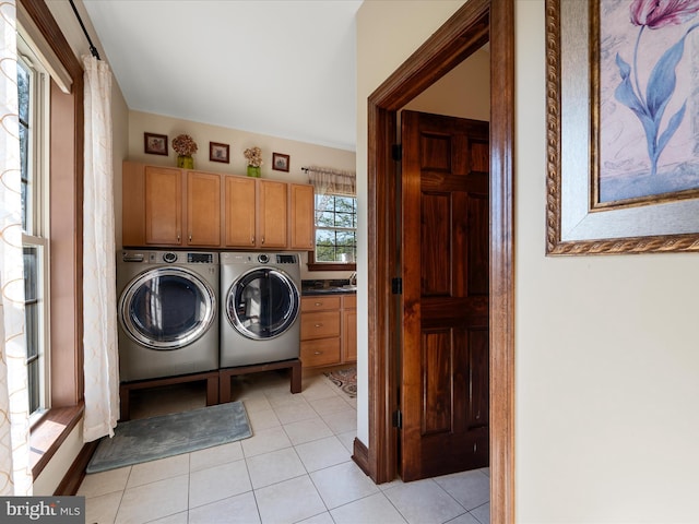 washroom with light tile patterned floors, cabinet space, and washer and clothes dryer