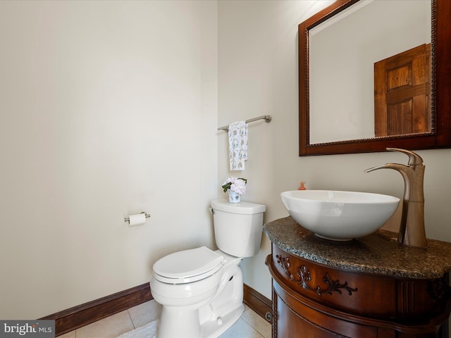 half bathroom with vanity, baseboards, toilet, and tile patterned floors